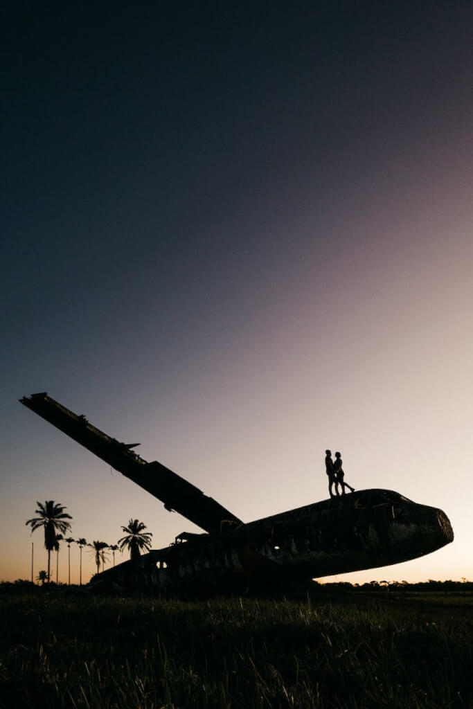 unrecognizable couple silhouettes embracing on damaged aircraft at night